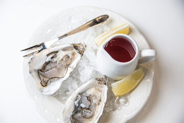 Fresh Oysters with ice lemon and sauce on white background
