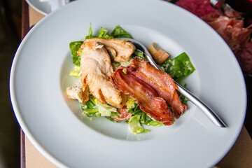 Salad with meat in a bowl. The waiter is holding a plate of salad close-up.