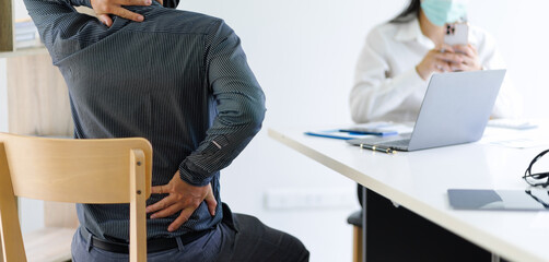 Men with health problems see a doctor for advice on treating back pain. Health care and medical...
