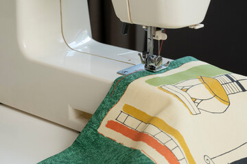 electric sewing machine close-up on a white background female hands sewing green fabric