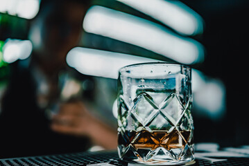 Whiskey glass with ice on bar counter