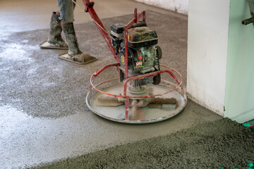 Fototapeta na wymiar Floor arrangement specialist, leveling the surface unevenness with a special machine after pouring the semi-dry screed during the construction phase. 