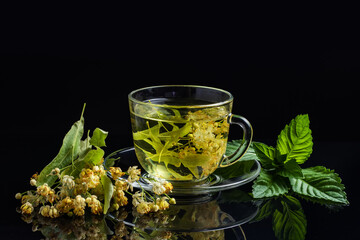 Cup of green tea and linden and mint on black background