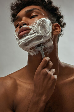 Partial of african american guy shaving with razor
