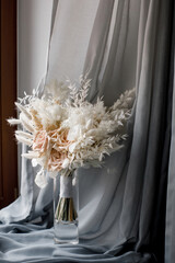 Delicate wedding bouquet in a vase on the curtain