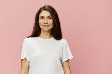 Fototapeta premium horizontal portrait of a cute attractive woman on a pink background in a clean white tank top smiling pleasantly at the camera