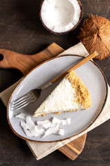 piece of coconut cheesecake on a plate with fresh coconut