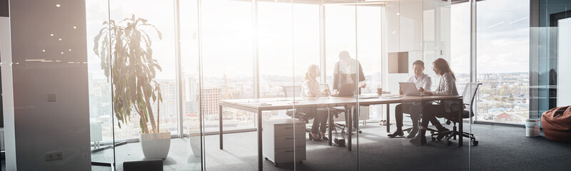 Team of businessmen communicating together after meeting in office with panoramic windows.