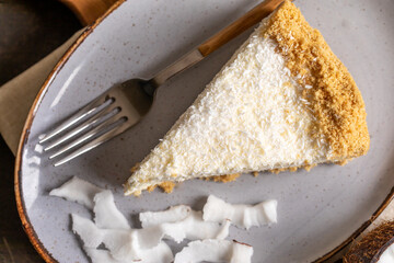 piece of coconut cheesecake on a plate with fresh coconut