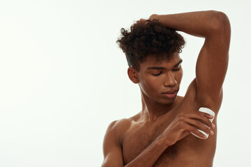 Obraz premium Young black guy applying deodorant on his armpit