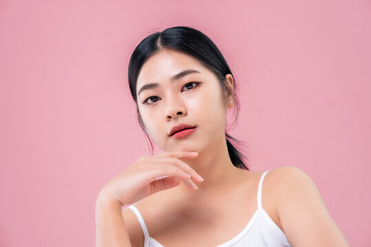 Beautiful Asian girl looking at camera isolated on pink background