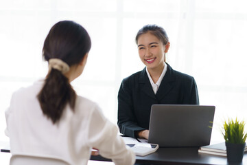 Two young Asian businesswomen discuss the concept of a new start-up project. Analyze marketing planning and financial statement at the office.