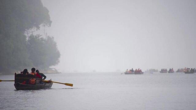 row boat in a foggy lake going towards crowded patch filled with boats as tourists fill up the popular hill station during the beautiful monsoons