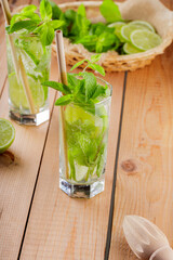 Mojito cocktail and ingredients on wooden boards. Two glasses of mojito with mint and lime. Summer drink with bamboo straw