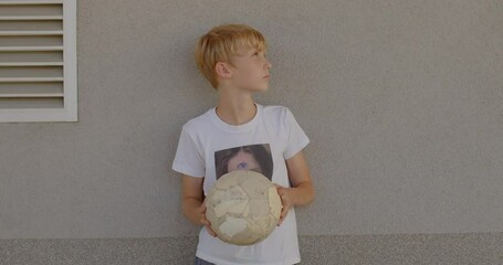 Portrait of posing cute teen boy with ball at summer during practice modeling classes. Space for text grey background. 