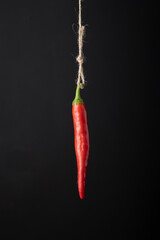 Chili pepper hanging on a rope on a black background