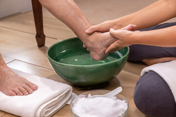 Obraz na płótnie Canvas Female caregiver wipes the elderly woman feet by towel.