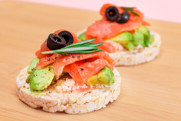 Rice Cake Sandwiches with Fresh Salmon, Avocado and Olives on Bamboo Cutting Board. Easy Breakfast. Diet Food. Quick and Healthy Sandwiches. Crispbread with Tasty Filling. Healthy Dietary Snack