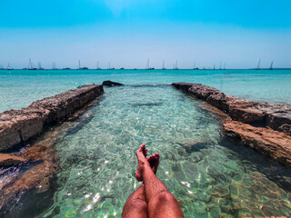 feet on a turquoise paradise beach and stone pool, Mallorca, Olalla Es Trench