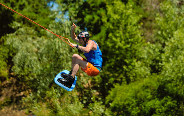 Professional wakeboarder jumping over the water against the sky and trees