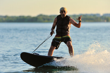 A professional wakeboarder rides on the lake in sunny weather, performing figures