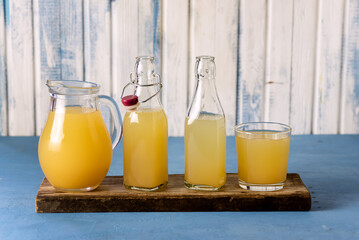 Glass Jug Bottles and Glass with Healthy Organic Apple Juice with Pulp on Wooden Tray Rustic Blue Background Healthy Detox Drink