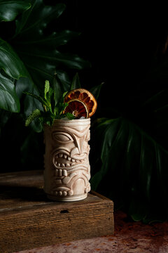 Dark and moody Tiki cocktail with dried fruit and mint garnish