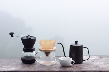 Drip coffee set on wooden table with foggy morning background