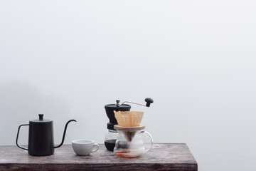 Drip coffee set on wooden table with foggy morning background