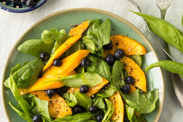 plate with salad with spinach, mango and blueberries close-up