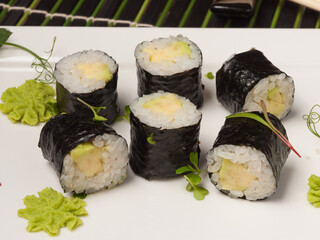 maki sushi rolls with avocado on a white plate. close-up