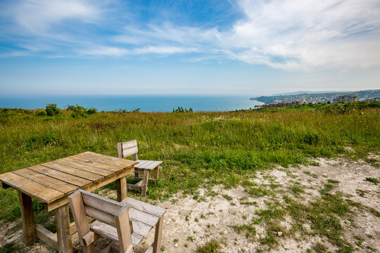 Primitive wooden planks table with two chair with a sea view, close to the sea shore, Byala, Bulgaria. Beautiful clouds. Spring afternoon.