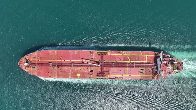 Aerial top down view at a bow of a container cargo ship traveling in full speed over blue ocean