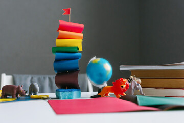 Boat made of colored paper, a rainbow flag, LGBT, autism stands on a table with books. Back to school.