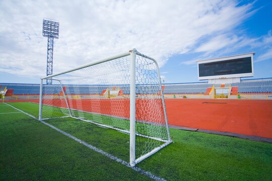 STADIUM - Football field with goal and tablo on blue sky