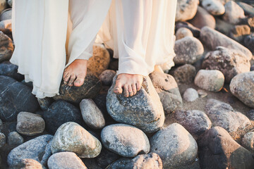 The bride stands barefoot on the stones