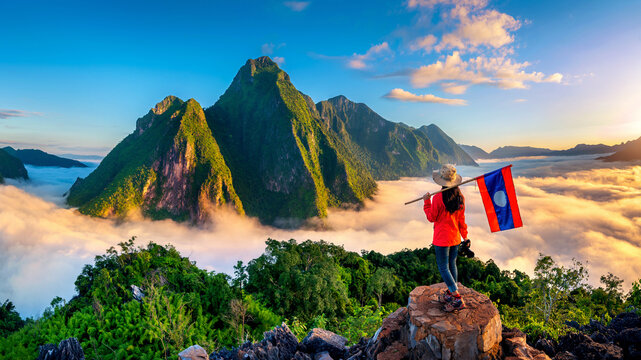 Tourist standing on Pha Dang viewpoint at sunrise in Muang Ngoy, Laos.