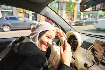 Arab woman hiding from the sun while driving a car