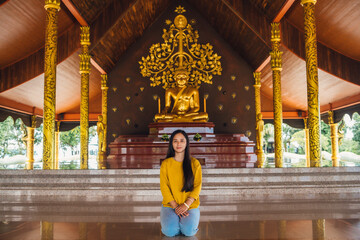 Asian woman sitting meditation and golden buddha statue in buddhist church at Wat sirindhorn wararam