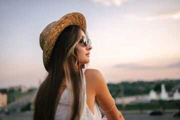 Portrait of a relaxed woman with hat looking forward at the horizon cityscape in the background copy space - 520354601
