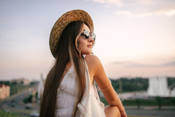 Portrait of a relaxed woman with hat looking forward at the horizon cityscape in the background copy space - 520354809