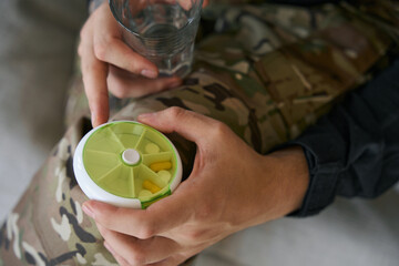 Serviceman holding round pill container and water glass