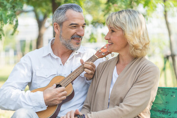 Elderly couple lifestyle concept. Husband embrace wife and sit on seat in the park relax on retirement life.