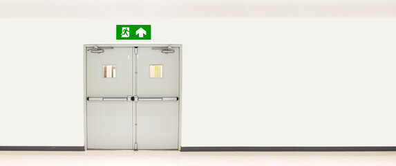 Green emergency fire exit sign or fire escape on ceiling for doorway or door exit in the building...