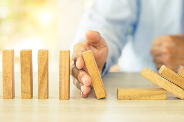 Close-up hand prevent wooden block not falling domino concepts of financial risk management and...