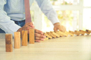 Close-up hand prevent wooden block not falling domino concepts of financial risk management and strategic planning and business challenge plan.