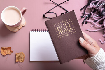 Holy Bible in female hand in sweater with a Cup of Coffee top view. Holy Bible study concept