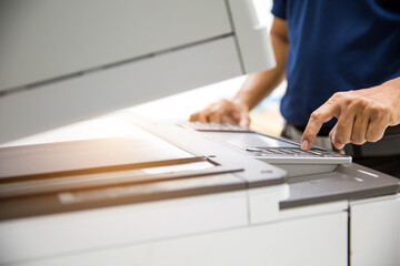 Photocopier printer, Close up hand office man press copy button on panel to using the copier or photocopy machine for scanning document or printing paper or Xerox a sheet. - obrazy, fototapety, plakaty