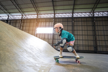 asian child or kid girl playing skateboard or riding surf skate up to wave ramp or wave bank to fun...