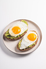 Avocado egg sandwich with a glass of water. Healthy light breakfast concept. Whole grain toasts with mashed avocado and fried eggs